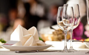 A table set with wine glasses and plates for a meal.
